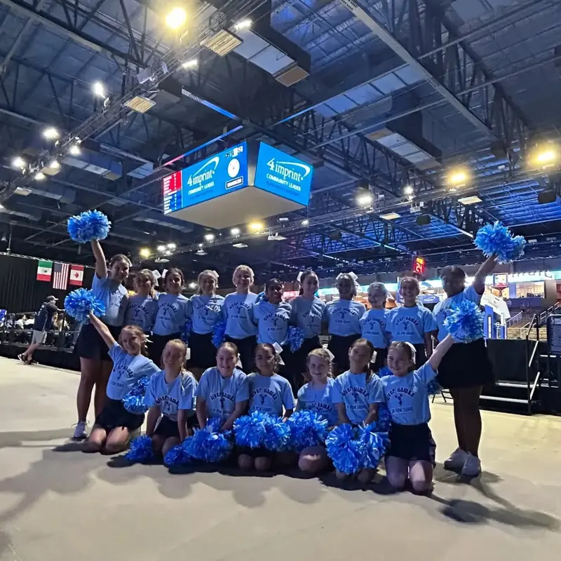 Creation Village cheer and pom students with blue pom-poms on the arena floor at Silver Spurs Arena