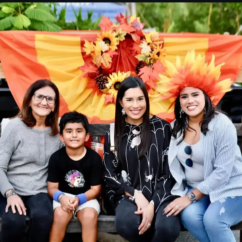 A family smiles in front of a fall leaves and sunflower display at a past Creation Village festival