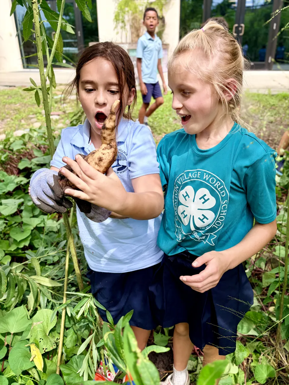 Two 4-H students holding sugarcane they harvested in the garden