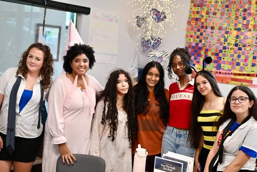 Upper school students in costume smiling together in a classroom