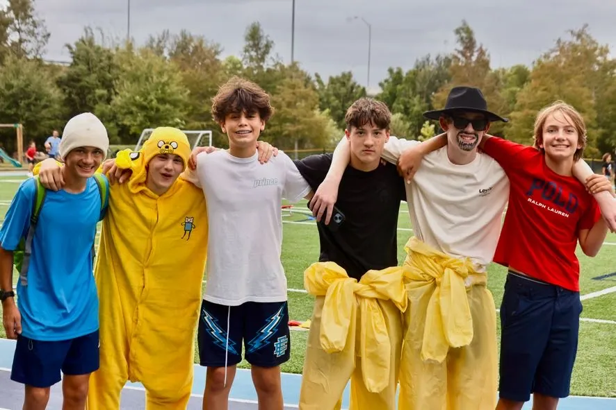 Upper school students in costume laughing together on the sports field