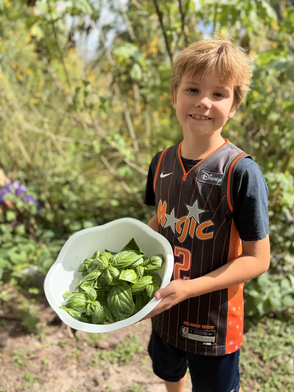 A Grade 3 student holding a bowl of freshly picked basil from the school garden