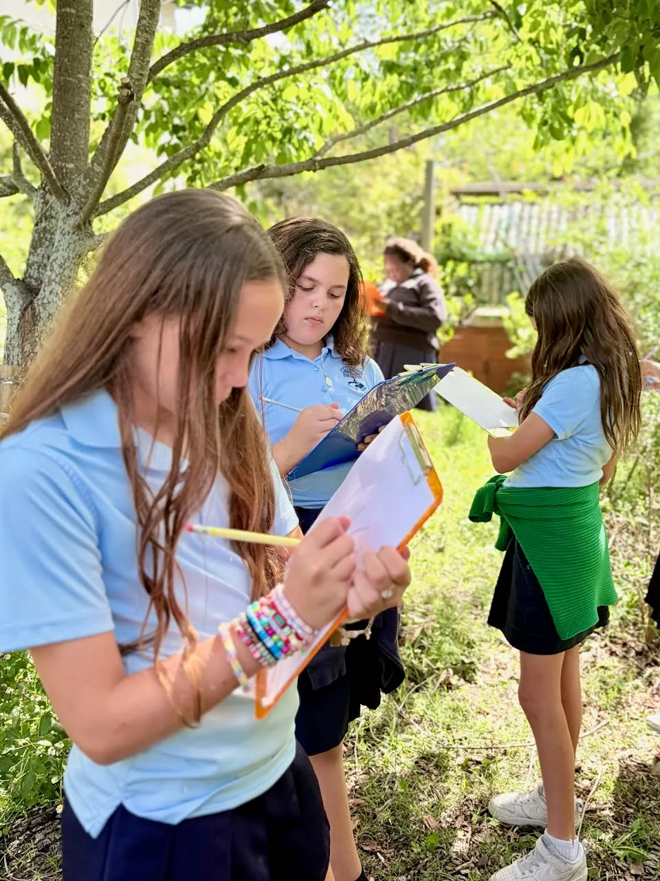 Middle school students recording observations on clipboards outdoors