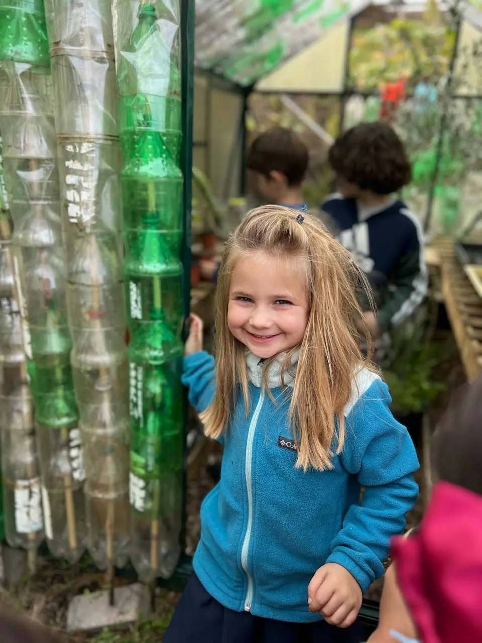 A smiling student in the bottle greenhouse