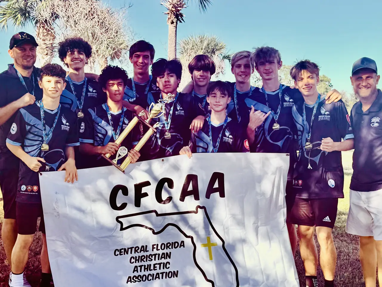 River Hawks players celebrating with the CFCAA banner and trophy
