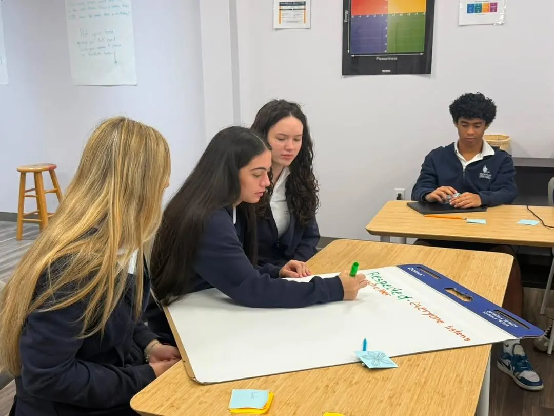 Upper school students planning together at a whiteboard