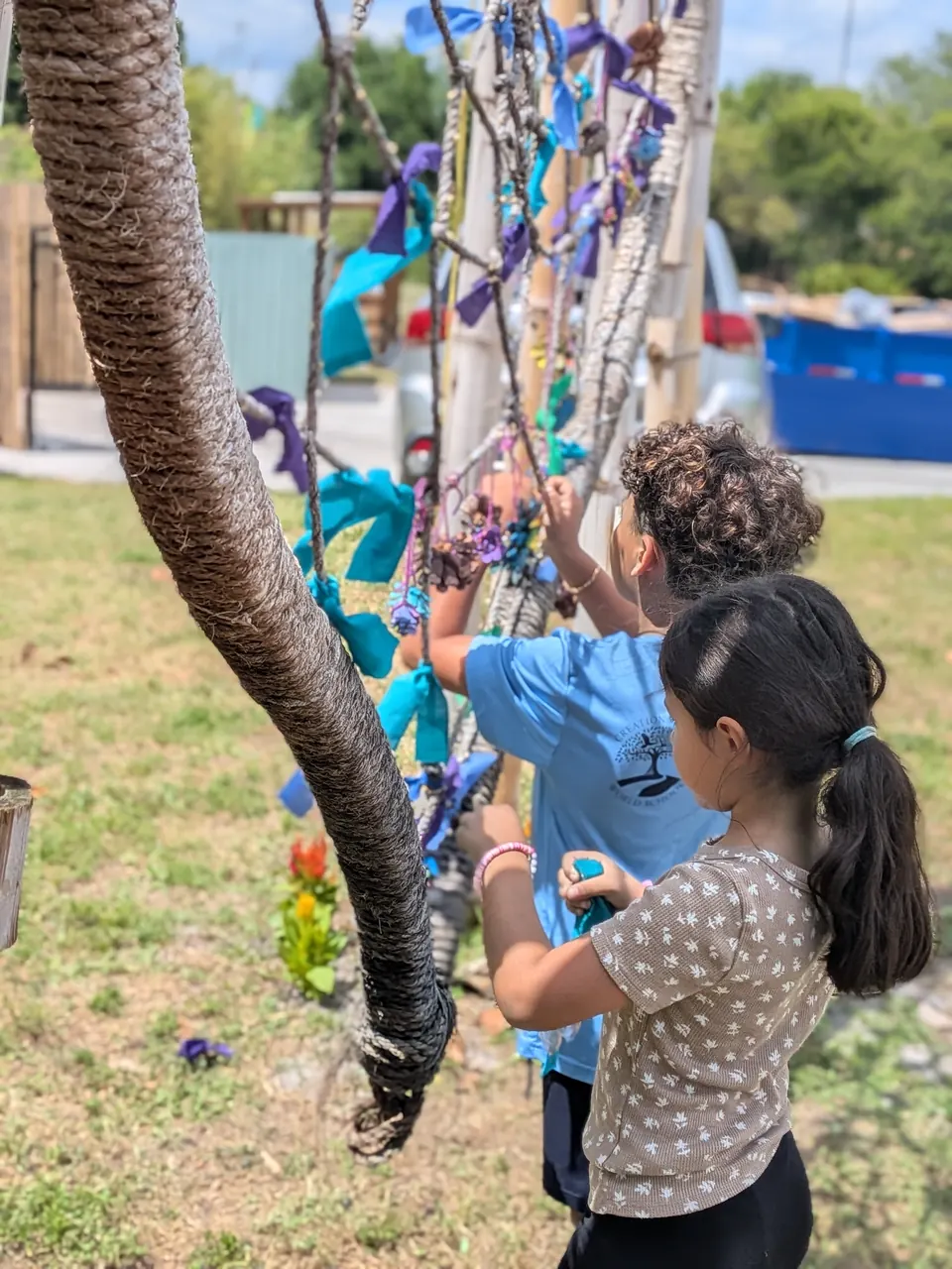 Primary students weaving yarn art outdoors